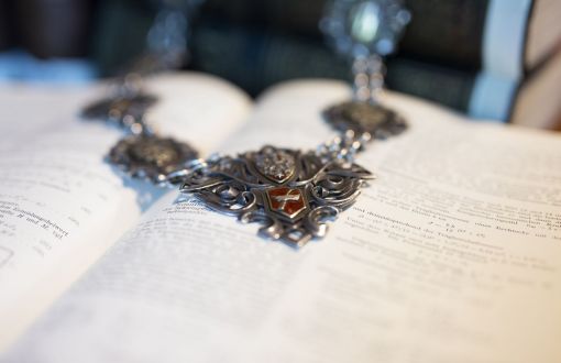 A fragment of the Rector's chain on an open book.