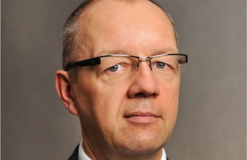 Zdjęcie portretowe: prof. dr hab. inż. Tomasz Kubiak w ciemnej marynarce, białej koszuli i krawacie na szarym tle.