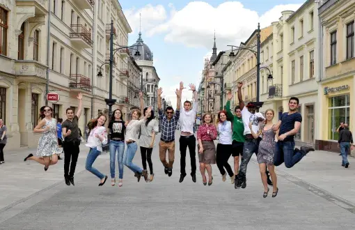 14 foreign students captured jumping in Piotrkowska Street on a sunny day.