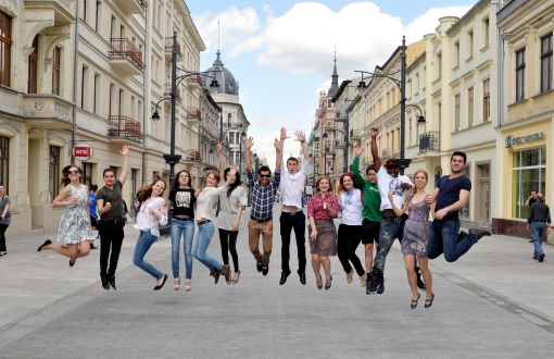 14 foreign students captured jumping in Piotrkowska Street on a sunny day.