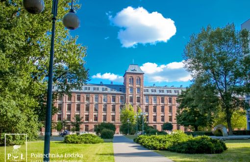 Kampus B Politechniki Łódzkiej: zielona trawa, drzewa, w tle ceglany Budynek Trzech Wydziałów.