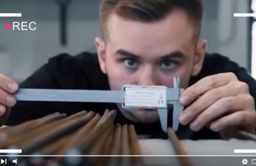 A frame from a promotional film: a student measuring a bronze element with a minimeter.