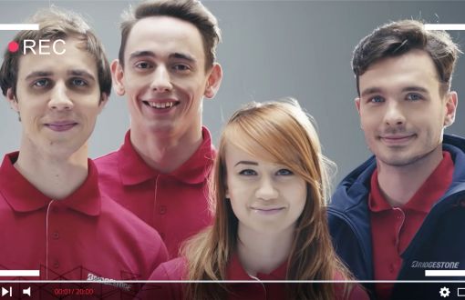 frame from promotional film: four students in maroon T-shirts against a grey background.