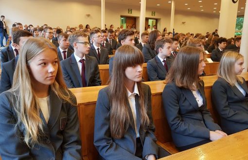 Uczniowie PLO PŁ w szarych, jednolitych marynarkach siedzą w rządach podczas inauguracji roku szkolnego.