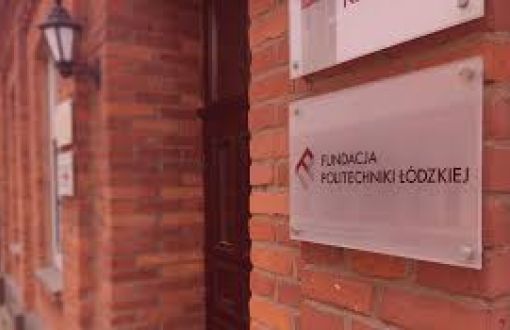 Ceglana ściana budynku, na niej biała tabliczka z napisem: Fundacja Politechniki Łódzkiej.