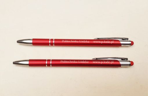 Dwa bordowe długopisy z napisem Politechnika Łódzka położone równolegle na jasnym tle 