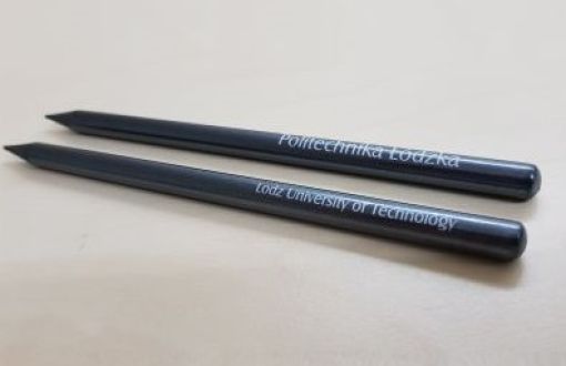 Two black pencils with the inscription Lodz University of Technology placed parallel on a light background.