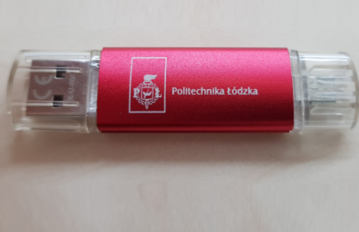 Rectangular flash drive in red with Lodz University of Technology logo and inscription. The ends of the drive have transparent caps.