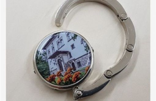 Silver-coloured bag hanger finished with a ring featuring a photograph of Willa J. Richter.