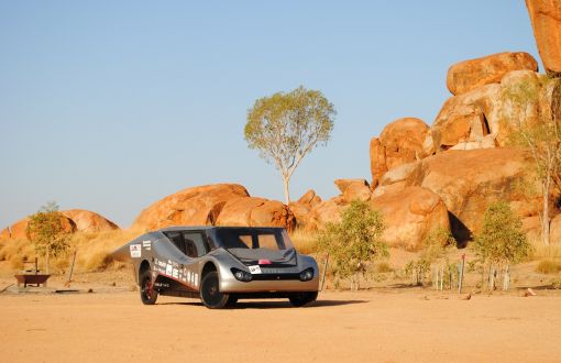 Srebrny Eagle Two - pojazd zespołu Lodz Solar Team, w australijskiej scenerii tj. na piasku, w tle skały o kolorze piasku.