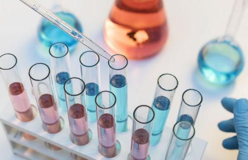 A dozen different coloured test tubes on a laboratory table.