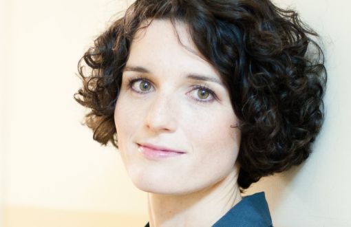 Zdjęcie portretowe: prof. Katarzyna Pernal stoi w niebieskiej koszuli na tle jasnej ściany.