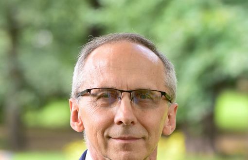 Zdjęcie portretowe: prof. Paweł Strumiłło w niebieskim garniturze i białej koszuli. W tle zieleń parku.