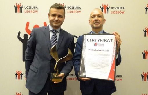 dr hab. inż. Andrzej Romanowski, prof. PŁ i prof. Rotta stoją na tle ścianki z logami nagrody Uczelnia liderów. Prorektor trzyma statuetkę, prof. Rotta certyfikat w srebrnej ramce.