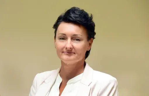 Zdjęcie portretowe: dr Ewa Brochocka w białej marynarce i koszuli na jasnym tle.