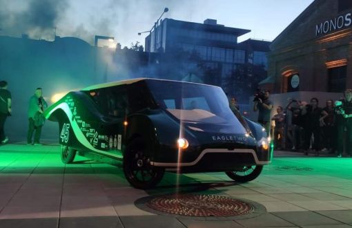 Eagle Two - elektryczny samochód zespołu Lodz Solar Team o nowoczesnym designie w kolorze zielonym na tle widzów i ceglanej zabudowy.