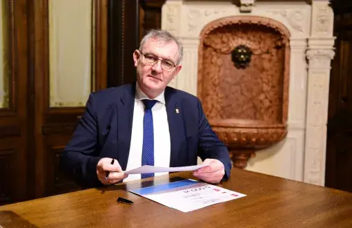 prof. Krzysztof Jóźwik w granatowym garniturze w swoim gabinecie, przy biurku podpisuje dokumenty.
