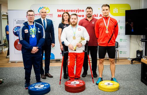 Czterech uczestników (oraz Prorektor ds. studenckich i trener) Integracyjnych Mistrzostw Polski AZS w podnoszeniu ciężarów dla osób z niepełnosprawnościami prezentują zdobyte medale.