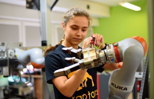 Studentka przy dłoni robota w laboratorium.