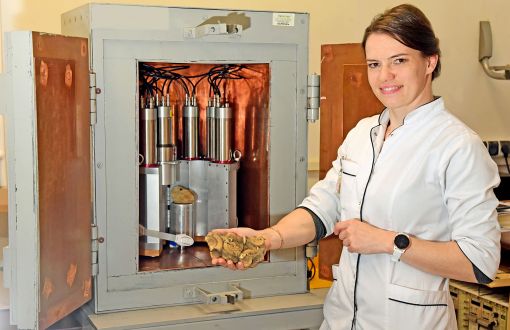 Prof. Magdalena Długosz-Lisiecka w białym fartuchu przy urządzeniu laboratoryjnym.