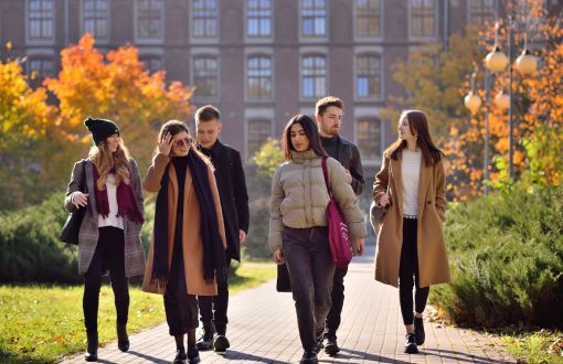 Sześcioro studentów Politechniki Łódzkiej spaceruje jesienią po kampusie.