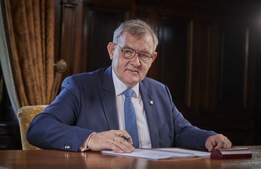 Prof. Krzysztof Jóźwik, rektor PŁ, siedzi przy biurku w swoim gabinecie i podpisuje dokumenty.