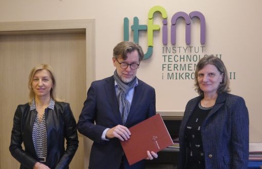 Prof. Grażyna Budryn, Janusz Olejnik i dr hab. inż. Agnieszka Nowak prof. PŁ stoją na tle ściany z logo Instytutu Technologii Fermentacji i Mikrobiologii.