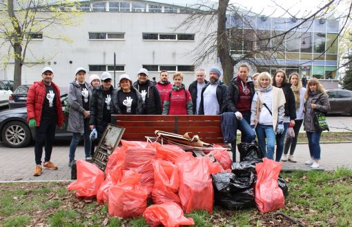 Uczestnicy akcji sprzątania świata. Przed nimi czerwone worki wypełnione śmieciami.