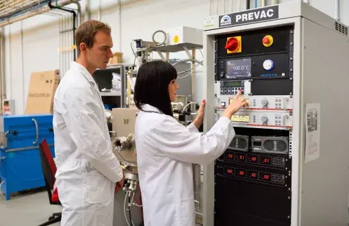 Studenci PŁ w białych fartuchach w laboratorium.