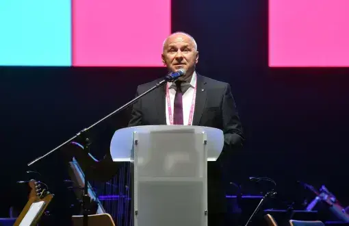 Adam Roczek stoi i przemawia przy mównicy.