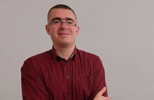 Zdjęcie portretowe: dr inż. Tomasz Boruta na szarym tle.