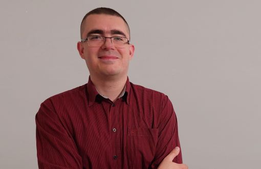 Zdjęcie portretowe: dr inż. Tomasz Boruta na szarym tle.