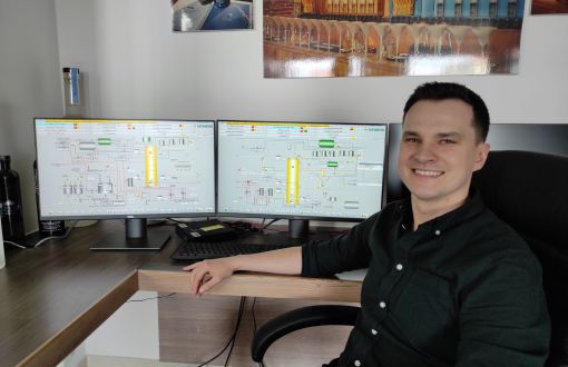 Mateusz Różański przy biurku z monitorami.