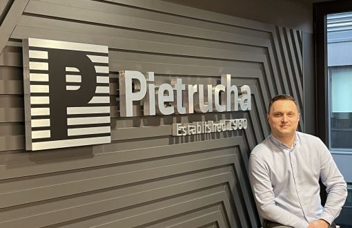 Michał Harendarz stoi przy ścianie z logotypem Pietrucha.