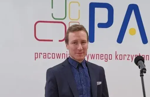 Mgr inż. Jan Makary Fryczak na tle ścianki reklamowej