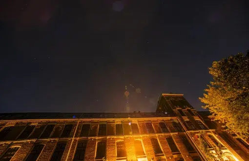 In the sky above the illuminated buildings, it is difficult to see the stars 