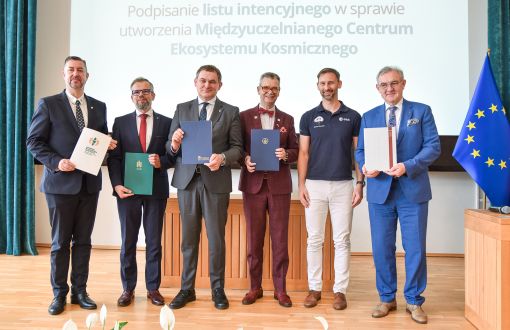 sześciu mężczyzn pozujących w rzędzie na tle banneru  i flagi UE