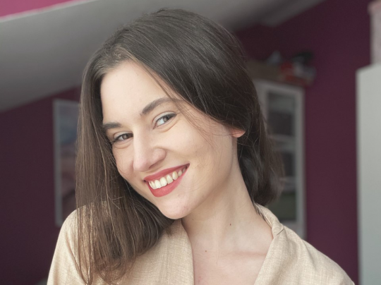 Portrait photo: smiling Wioletta Chmurska. The purple walls of the room in the background.